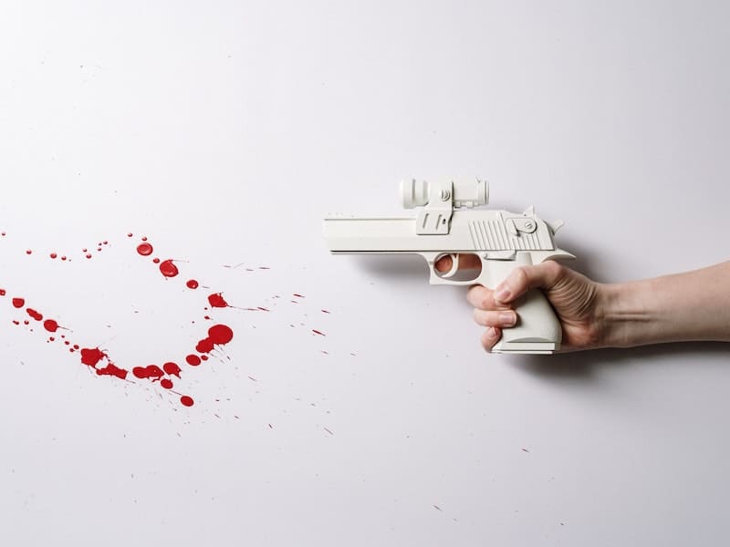 uma pessoa segurando uma arma branca com respingos de sangue após matar alguém