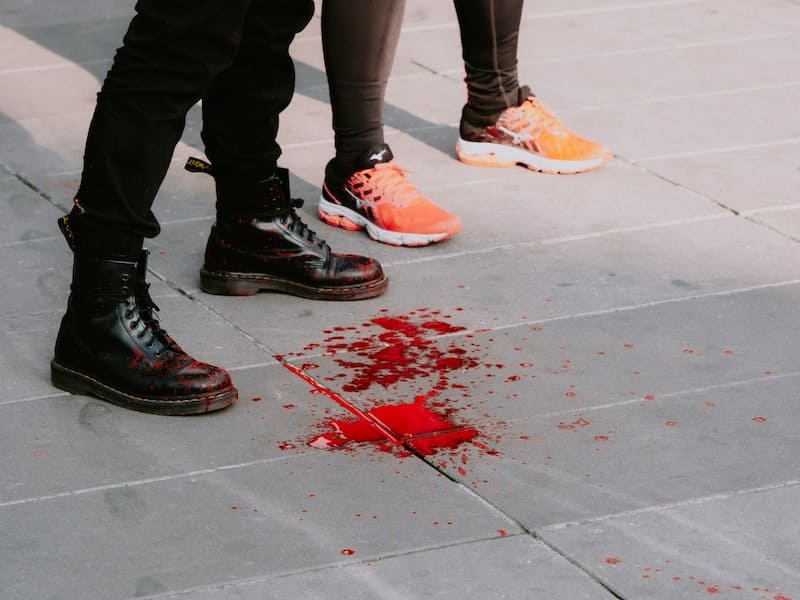 duas pessoas mostrando apenas seus pés e sangue no chão
