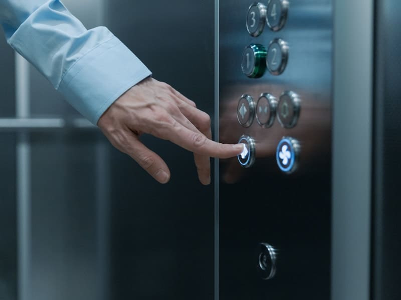 uma mão masculina apertando o botão de um elevador novo