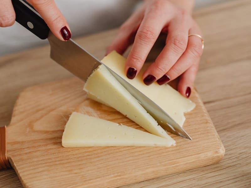 ṕessoa usando uma faca pequena para cortar queijo