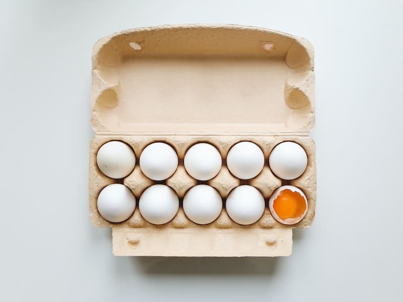cartela de ovos com um ovo aberto